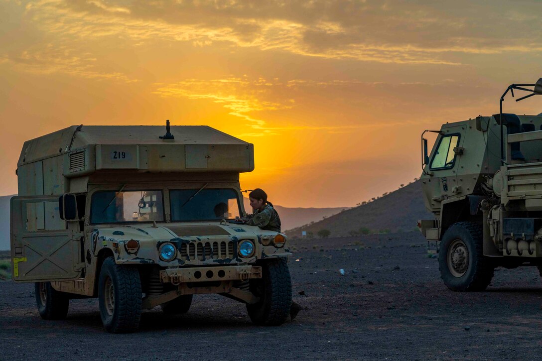 A soldier stands outside of a military vehicle.