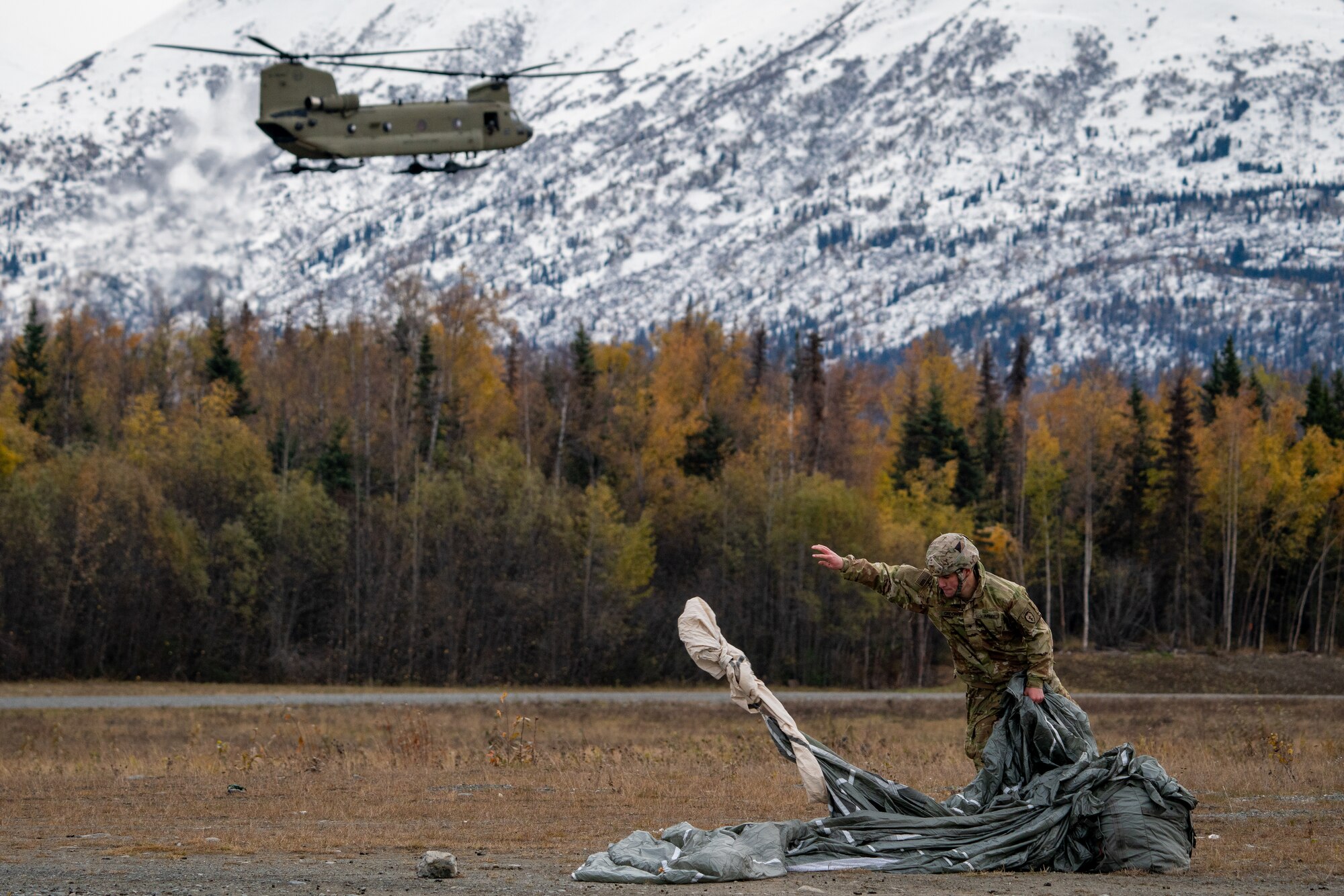 A U.S. Army paratrooper assigned to the 1st Squadron (Airborne), 40th Cavalry Regiment, 4th Infantry Brigade Combat Team (Airborne), 25th Infantry Division, U.S. Army Alaska, recovers his parachute after jumping from a CH-47 Chinook