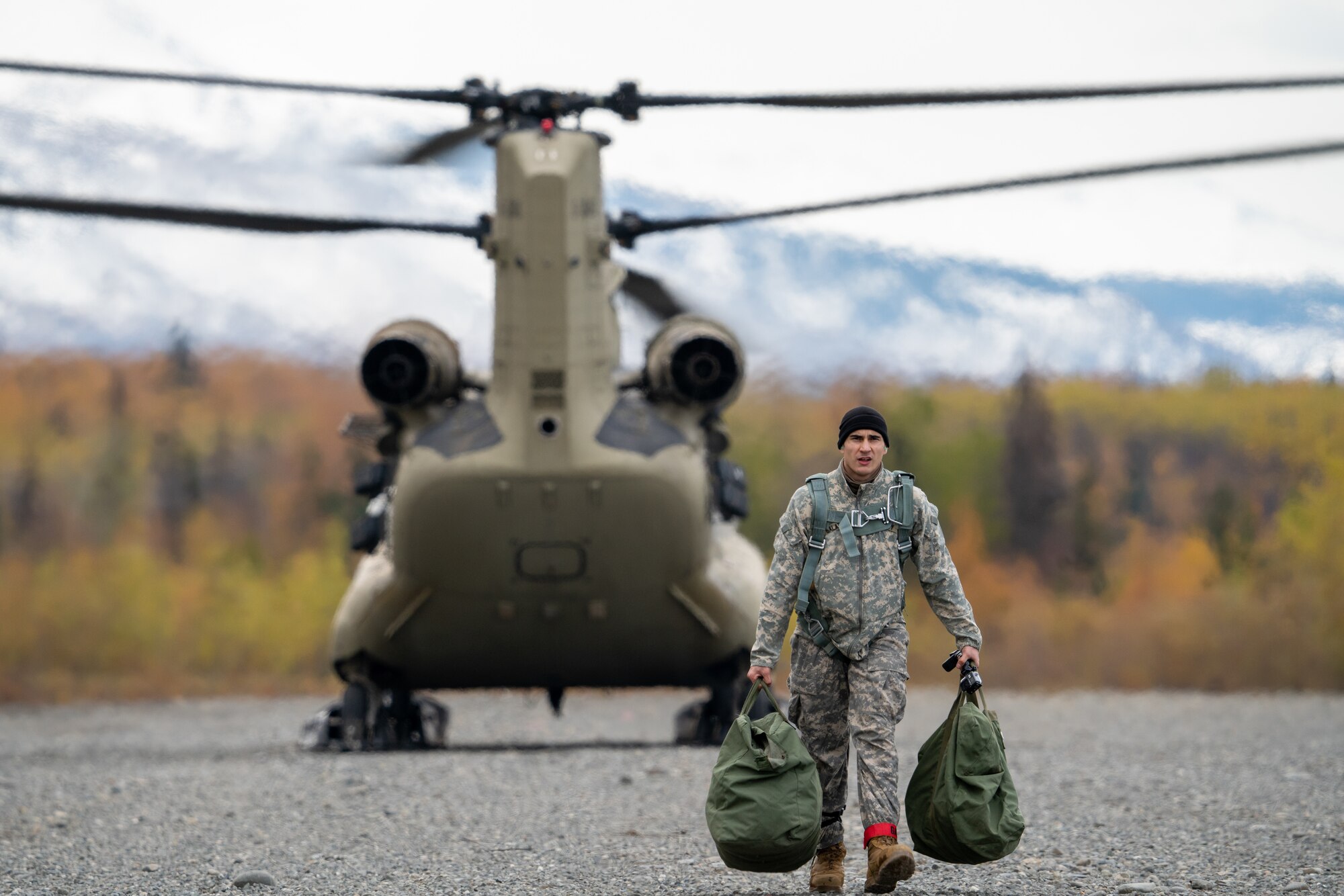 A U.S. Army paratrooper assigned to the 4th Infantry Brigade Combat Team (Airborne), 25th Infantry Division, U.S. Army Alaska, carries spare parachutes back from a CH-47 Chinook.