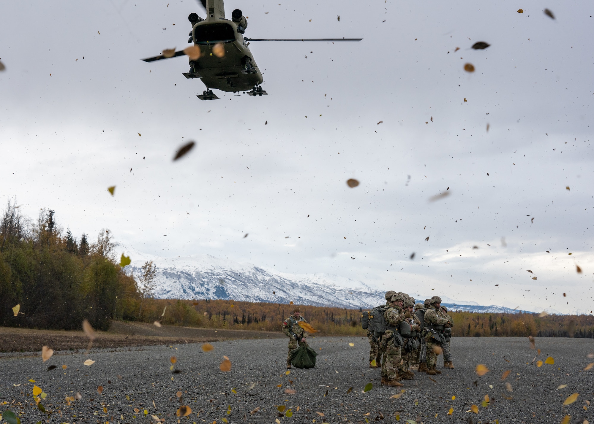 U.S. Army paratroopers assigned to the 4th Infantry Brigade Combat Team (Airborne), 25th Infantry Division, U.S. Army Alaska, brace against the rotor wash while waiting for a CH-47 Chinook.