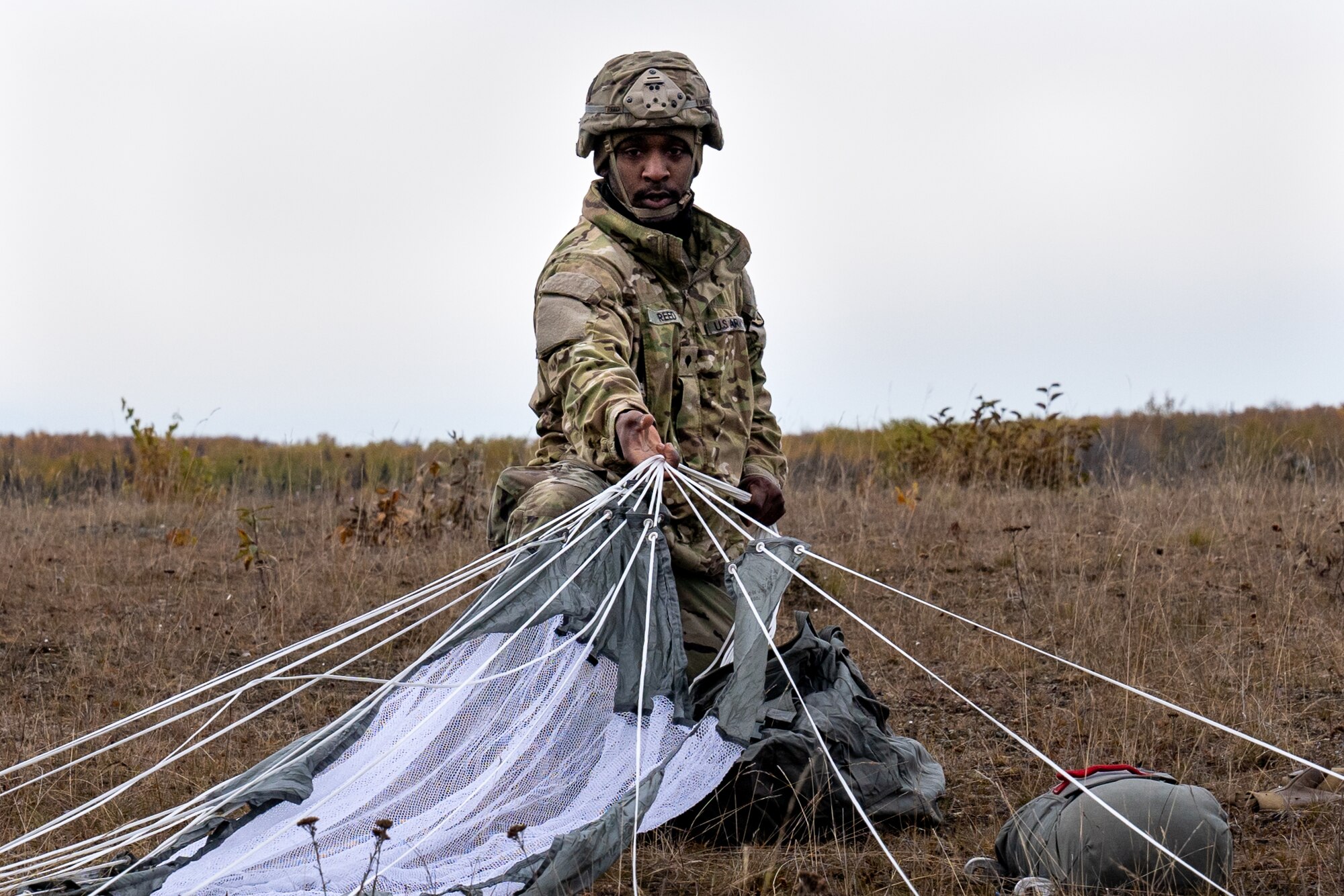 A U.S. Army paratrooper assigned to the 1st Squadron (Airborne), 40th Cavalry Regiment, 4th Infantry Brigade Combat Team (Airborne), 25th Infantry Division, U.S. Army Alaska, recovers his parachute after jumping from a CH-47 Chinook.