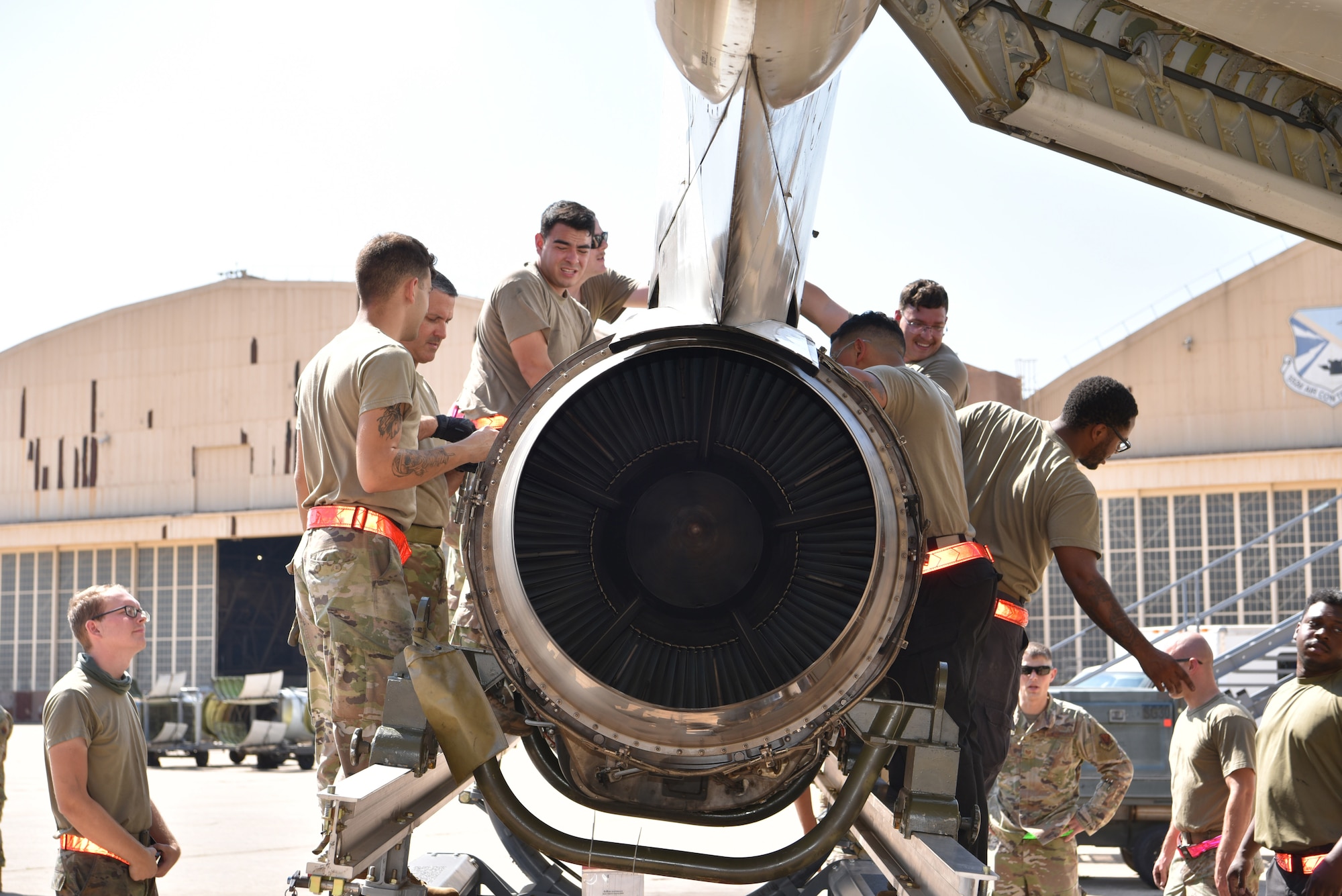 Maintenance crew attaching an engine to jet