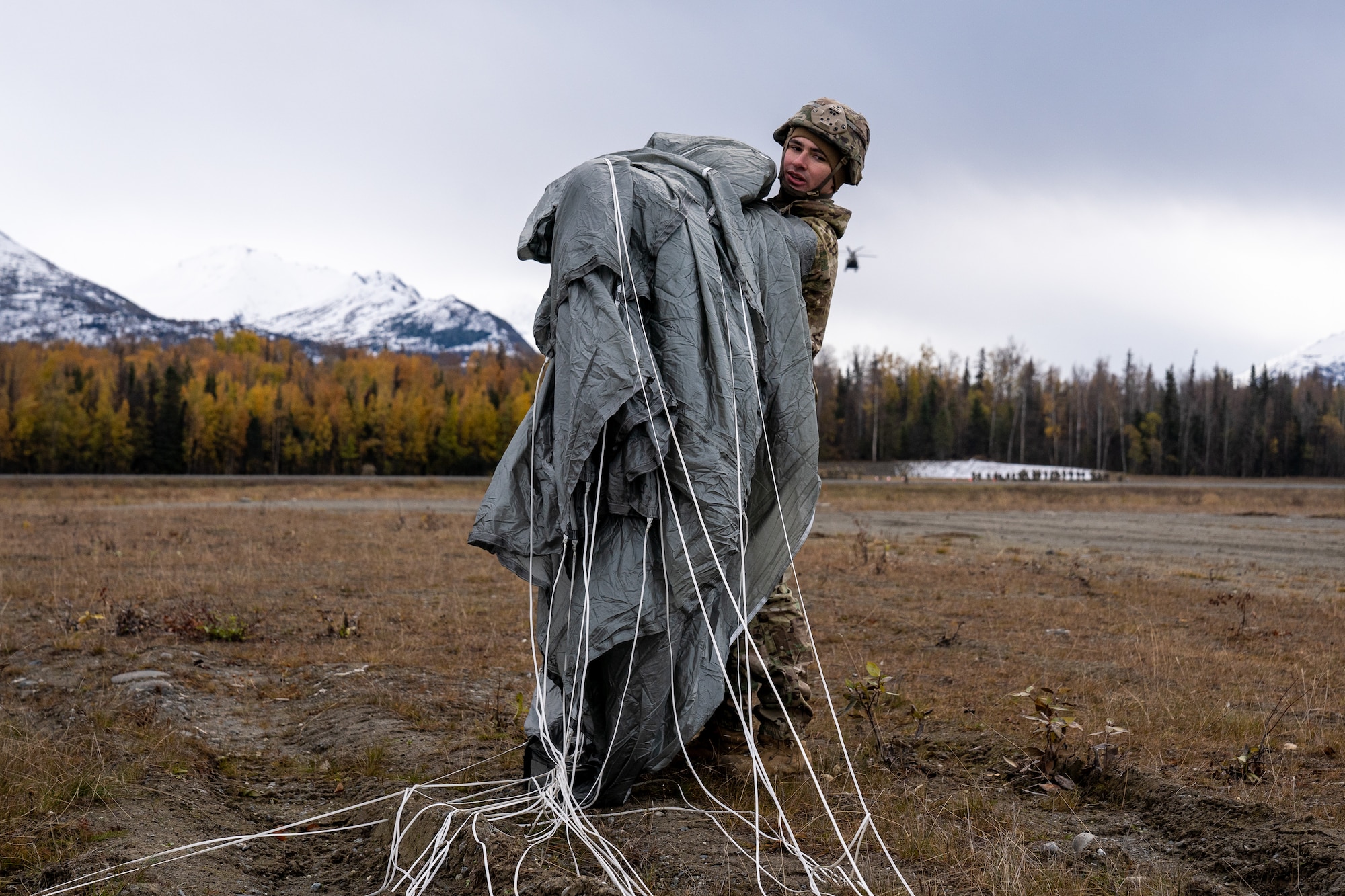 U.S. Army Spc. Chris Pulsipher, a paratrooper assigned to the 1st Squadron (Airborne), 40th Cavalry Regiment, 4th Infantry Brigade Combat Team (Airborne), 25th Infantry Division, U.S. Army Alaska, recovers his parachute after jumping from a CH-47 Chinook.