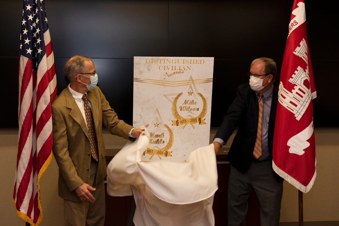 Mike Wilson (Right) and Mark Kuhlo, 2021 Distinguished Civilian Employee Recognition Award recipients, unveil a poster signifying the accolade during an award ceremony Oct. 6, 2021 at the Nashville District Headquarters in Nashville, Tennessee. Wilson retired in 2017 following 42 years of federal service, culminating his career as deputy district engineer for Project Management. Kuhlo retired in 2016 following 35 years of federal service, culminating his career as chief of the Electrical and Mechanical Branch. (USACE Photo by Lee Roberts)