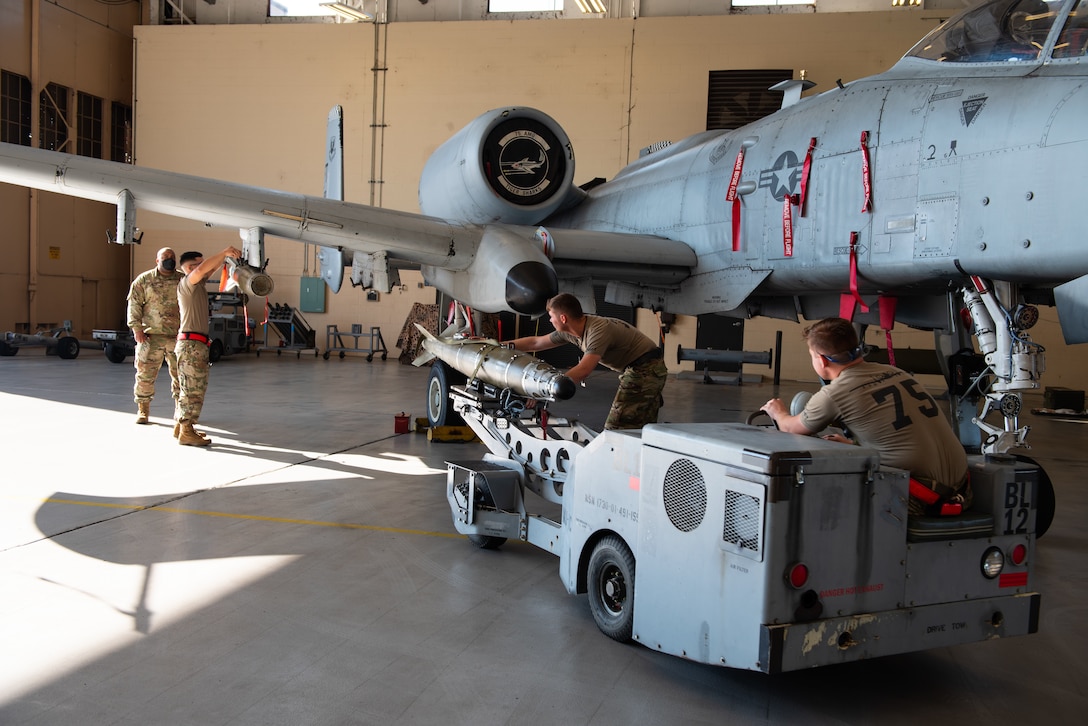 two men guiding missile onto a plane