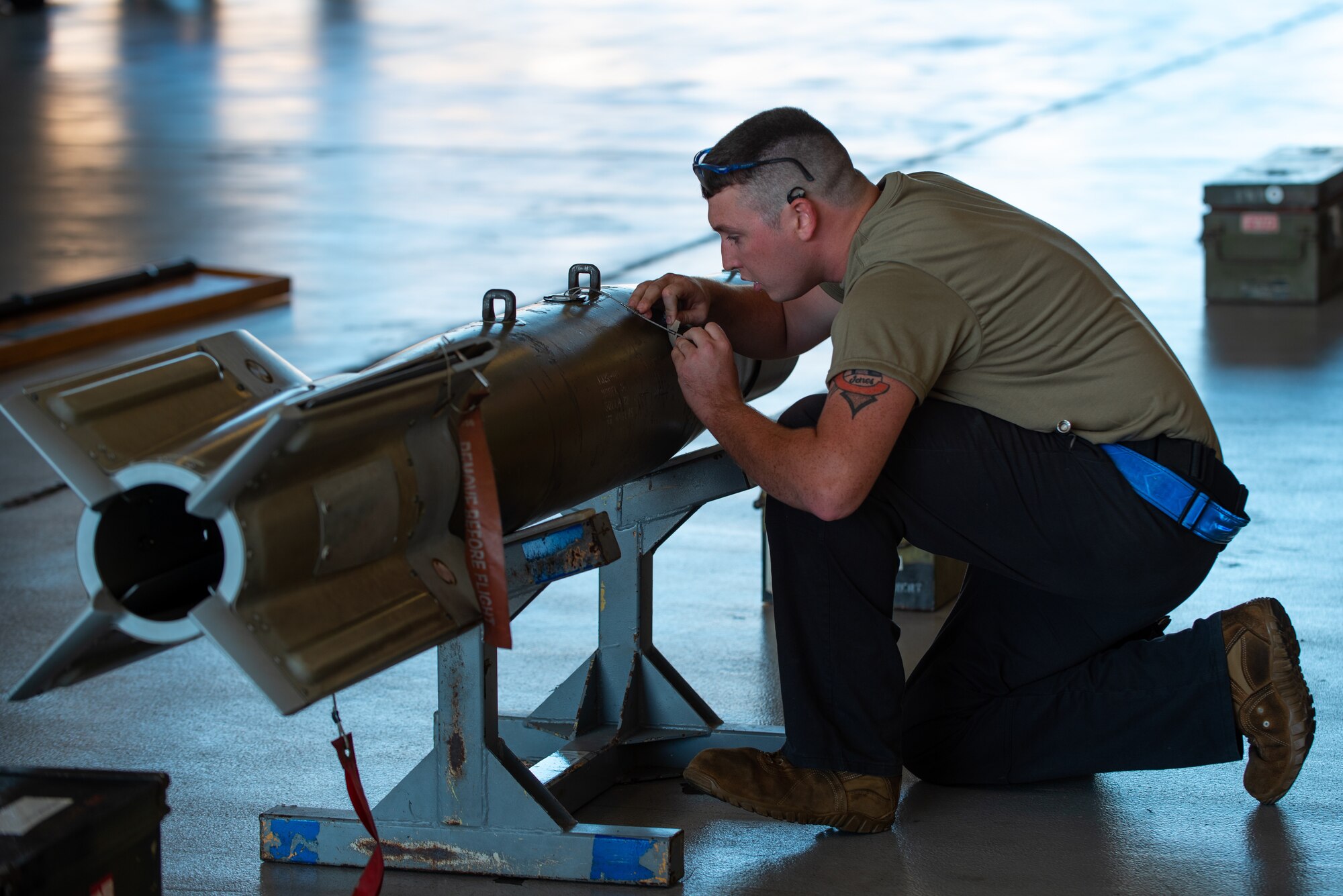 man kneeling next to a missile