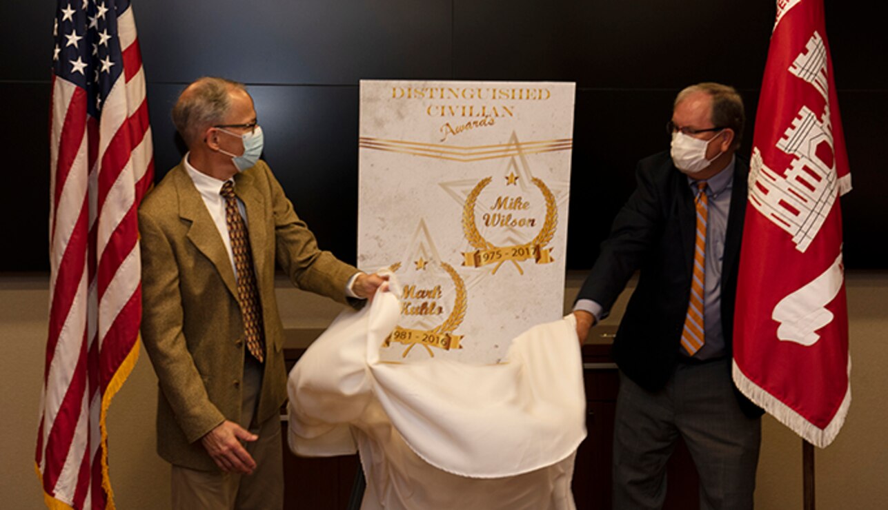Mike Wilson (Right) and Mark Kuhlo, 2021 Distinguished Civilian Employee Recognition Award recipients, unveil a poster signifying the accolade during an award ceremony Oct. 6, 2021 at the Nashville District Headquarters in Nashville, Tennessee. Wilson retired in 2017 following 42 years of federal service, culminating his career as deputy district engineer for Project Management. Kuhlo retired in 2016 following 35 years of federal service, culminating his career as chief of the Electrical and Mechanical Branch. (USACE Photo by Lee Roberts)