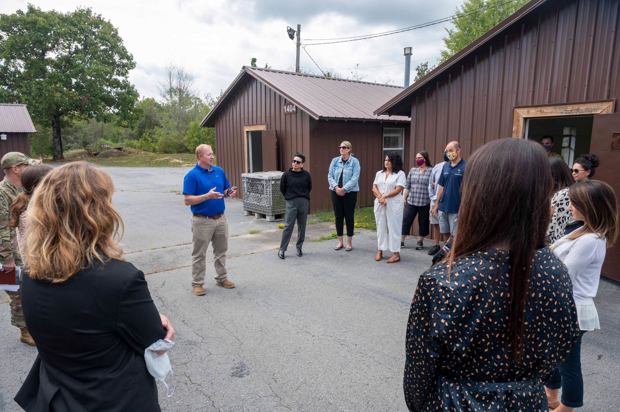 Military spouses stand in camp warlord while receiving a briefing.