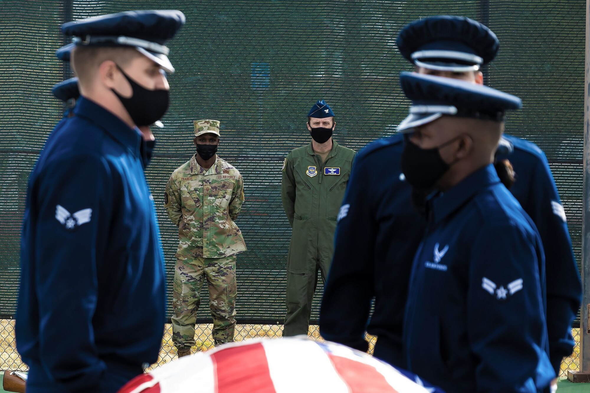 Airmen in Guardsmen attire line along a training casket while two men in military uniforms look on from the background
