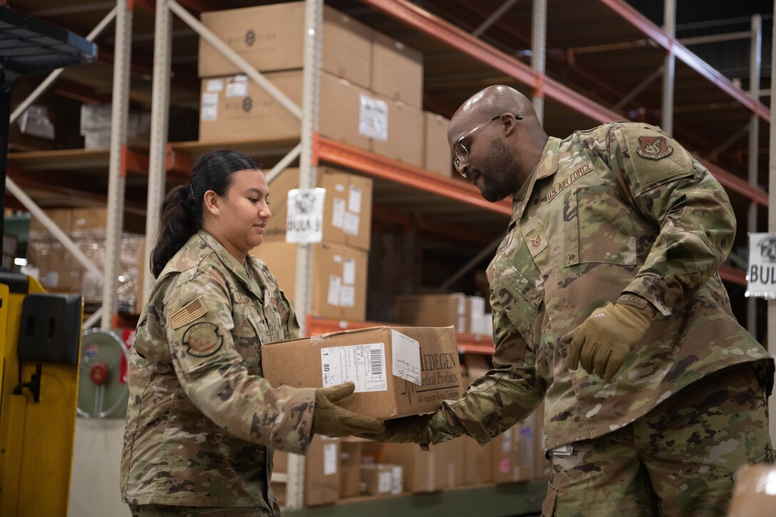 One airman hands a supply box off to another.