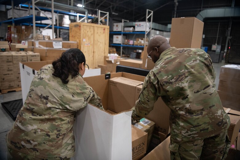 Two airmen fill a medical supply box