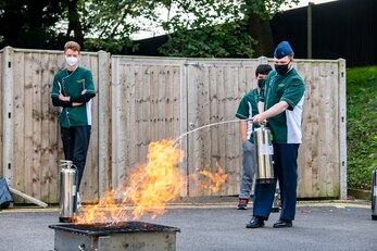 A student from the Alconbury Middle Highschool extinguishes a fire during safety training at RAF Alconbury, England, Oct. 4,2021. The training was a part of Fire Prevention Week which allowed firefighters from the 423rd CES to educate Airmen and family members from the 501st Combat Support Wing on proper fire safety habits. (U.S. Air Force photo by Senior Airman Eugene Oliver)