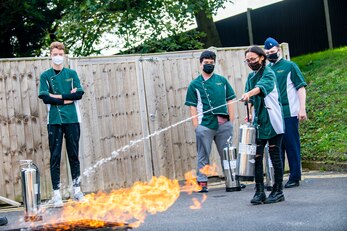 A student from the Alconbury Middle Highschool, extinguishes a fire during safety training at RAF Alconbury, England, Oct. 4,2021. The training was a part of Fire Prevention Week which allowed firefighters from the 423rd CES to educate Airmen and family members from the 501st Combat Support Wing on proper fire safety habits. (U.S. Air Force photo by Senior Airman Eugene Oliver)