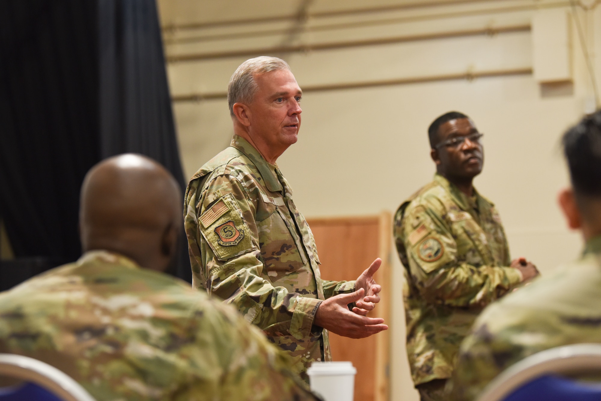 A man in uniform speaks in front a group.