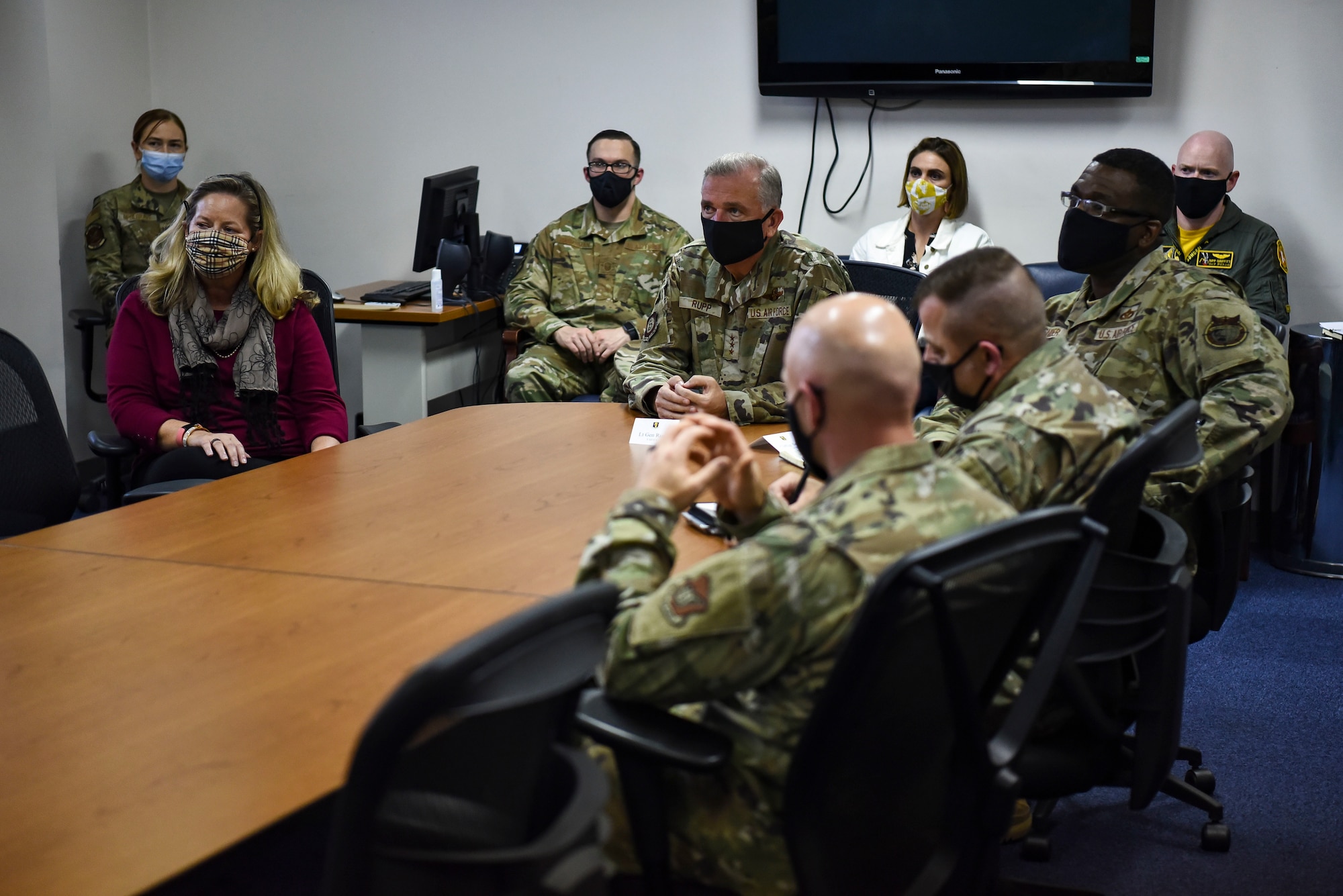 Group of military members in uniform sit in a conference room during a brief.