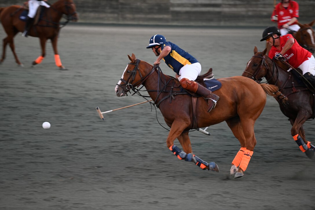 A man rides a horse as they chase a ball during a polo match.