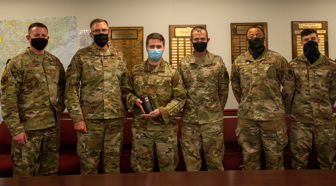 An Airman poses for a photo along with his leadership