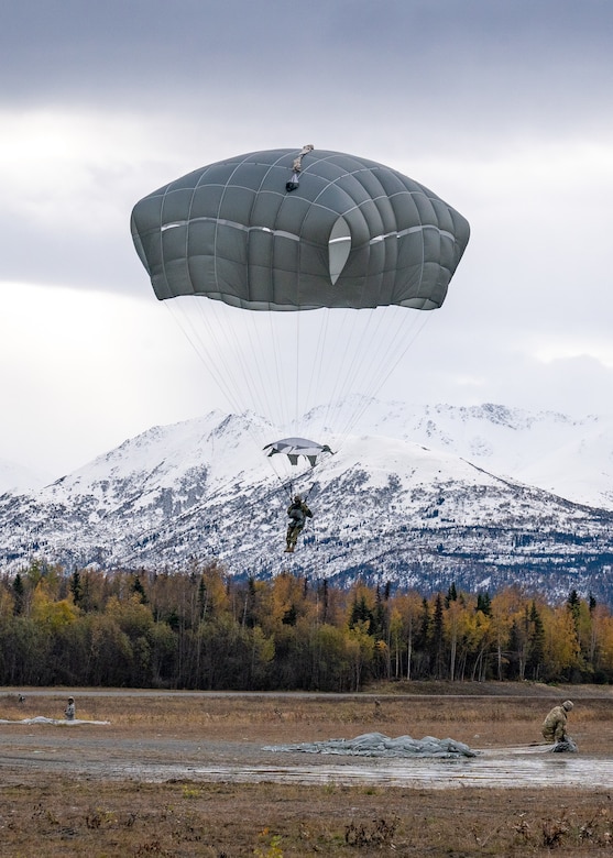 A soldier descends in the sky wearing a parachute.