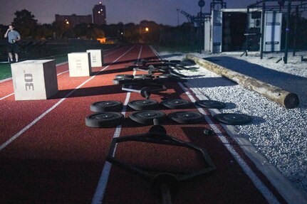 workout equipment (weights, bars, boxes) are laid out next to football field