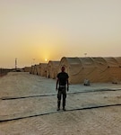 Man poses for picture amidst tents