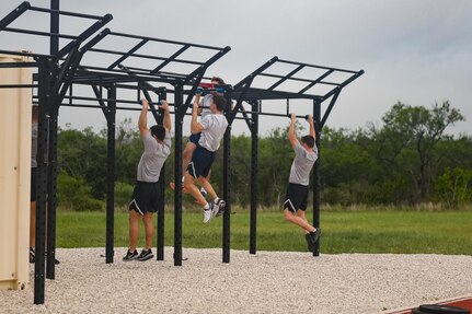 Three Airmen performing pullups