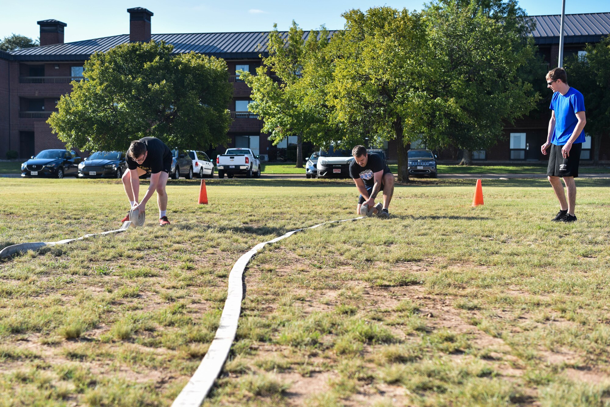 Fire Muster Challenge participants roll fire hoses during the Annual Fire Muster Challenge on Goodfellow Air Force Base, Texas, Oct. 8, 2021. The team to complete the six activities in the quickest time was crowned the winner. (U.S. Air Force photo by Senior Airman Jermaine Ayers)