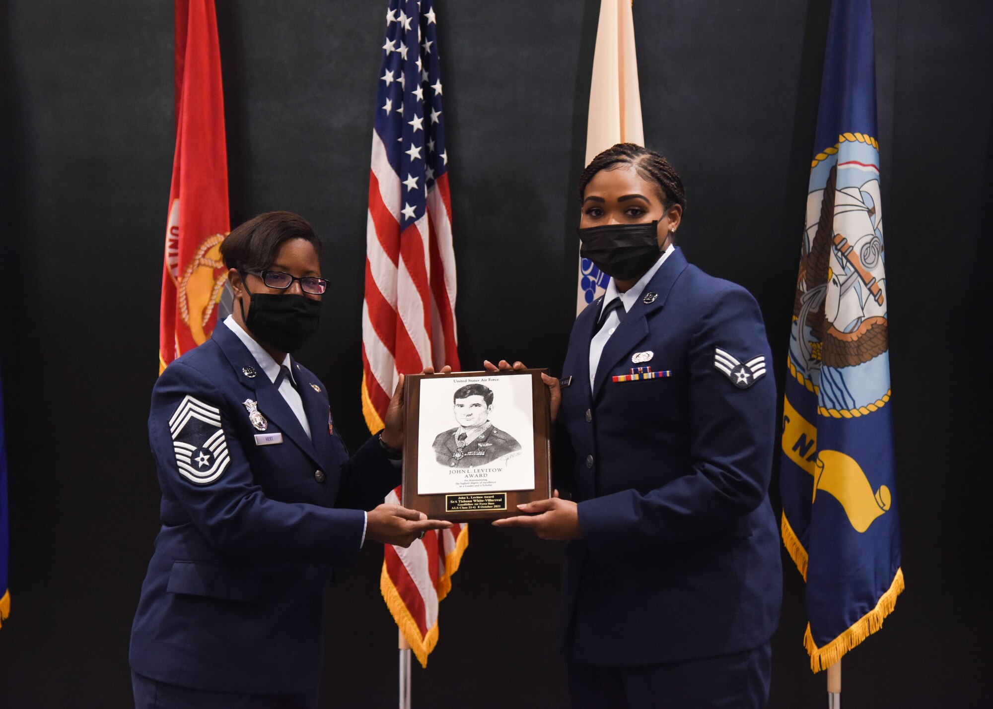 U.S. Air Force Chief Master Sgt. Chasity Hert, 17th Security Forces Squadron manager, presents Senior Airman Tishona White-Villarreal, 17th Communications Squadron knowledge operations manager the John L. Levitow award during The Airman Leadership School graduation ceremony on Goodfellow Air Force Base, Texas, Oct. 8, 2021. The John L. Levitow award is the highest award in professional military education and presented to the student who demonstrates the most outstanding leadership and scholastic achievement. (U.S. Air Force photo by Staff Sgt. Tyrell Hall)