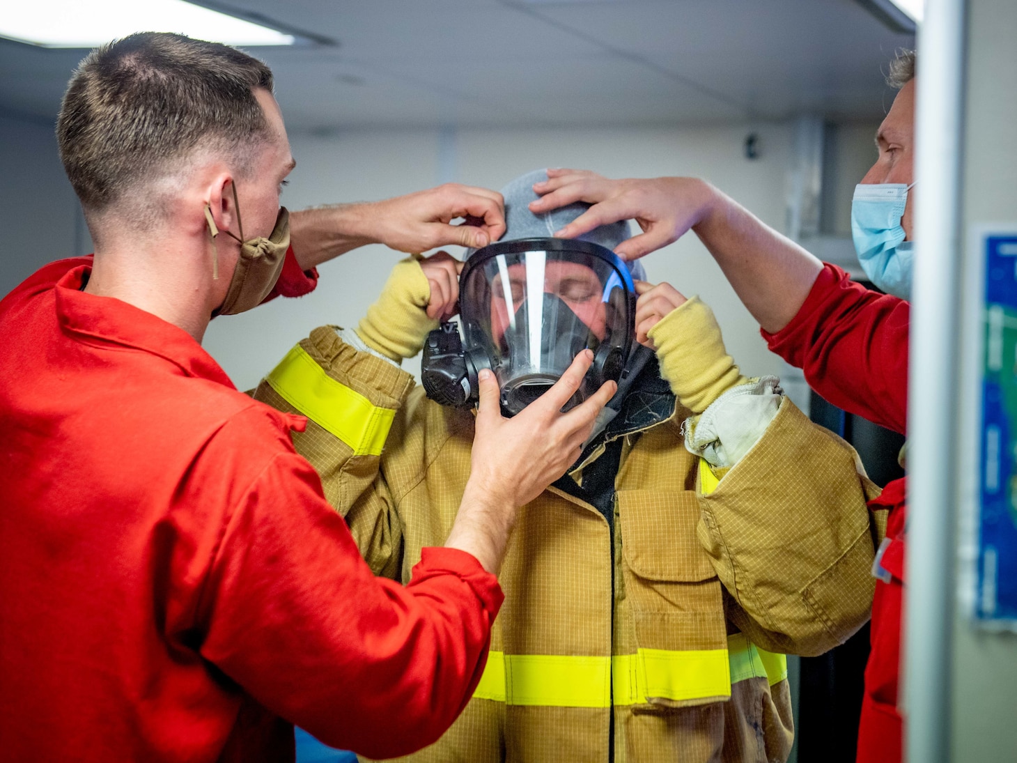 Mineman Seaman Timothy Messick, from Panama City, Fla., center, dons firefighting equipment during a damage control training exercise aboard the Independence-variant littoral combat ship USS Charleston (LCS 18).