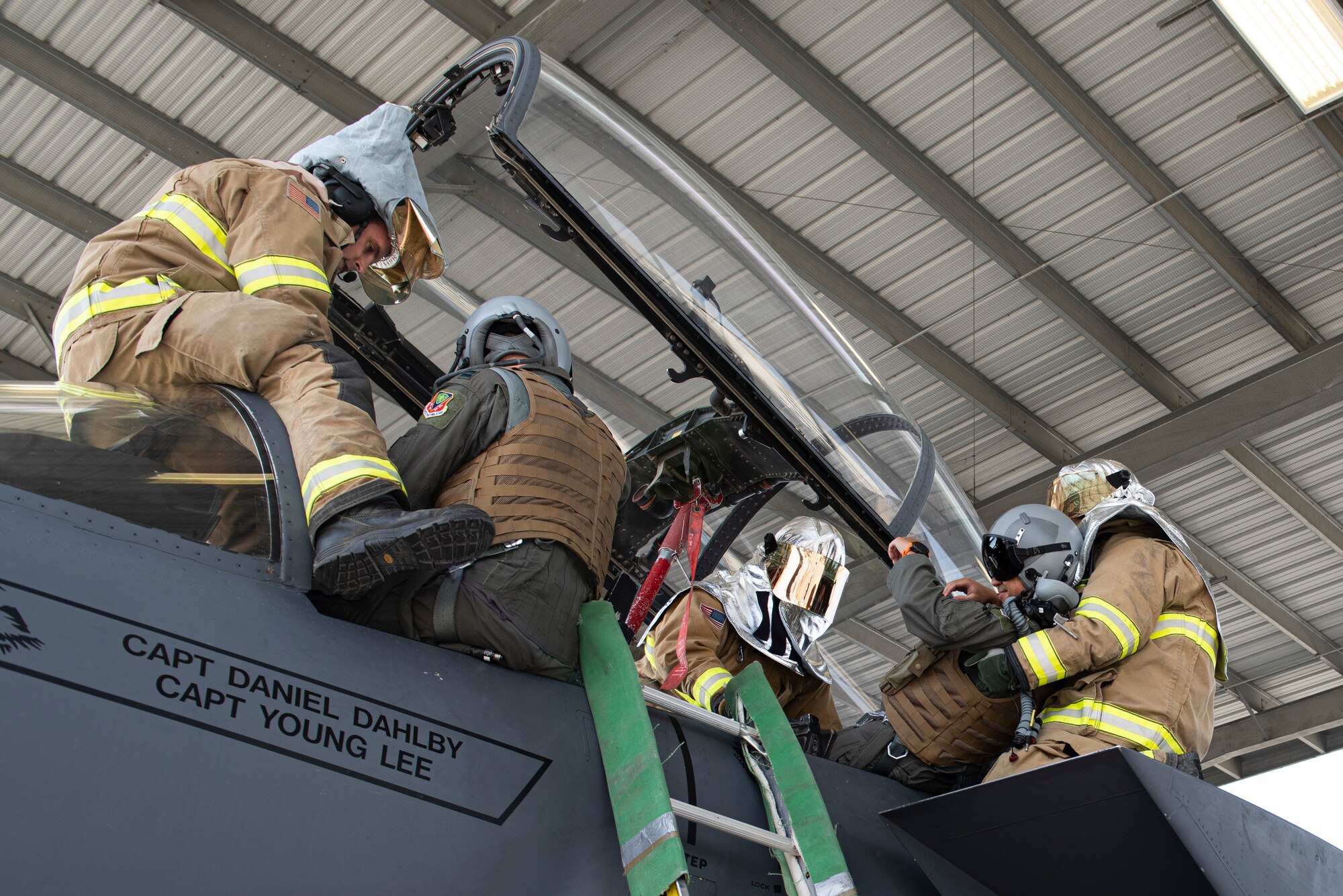 Four Fireman pull two simulated incapacitated aircrew members from an F-15E Strike Eagle