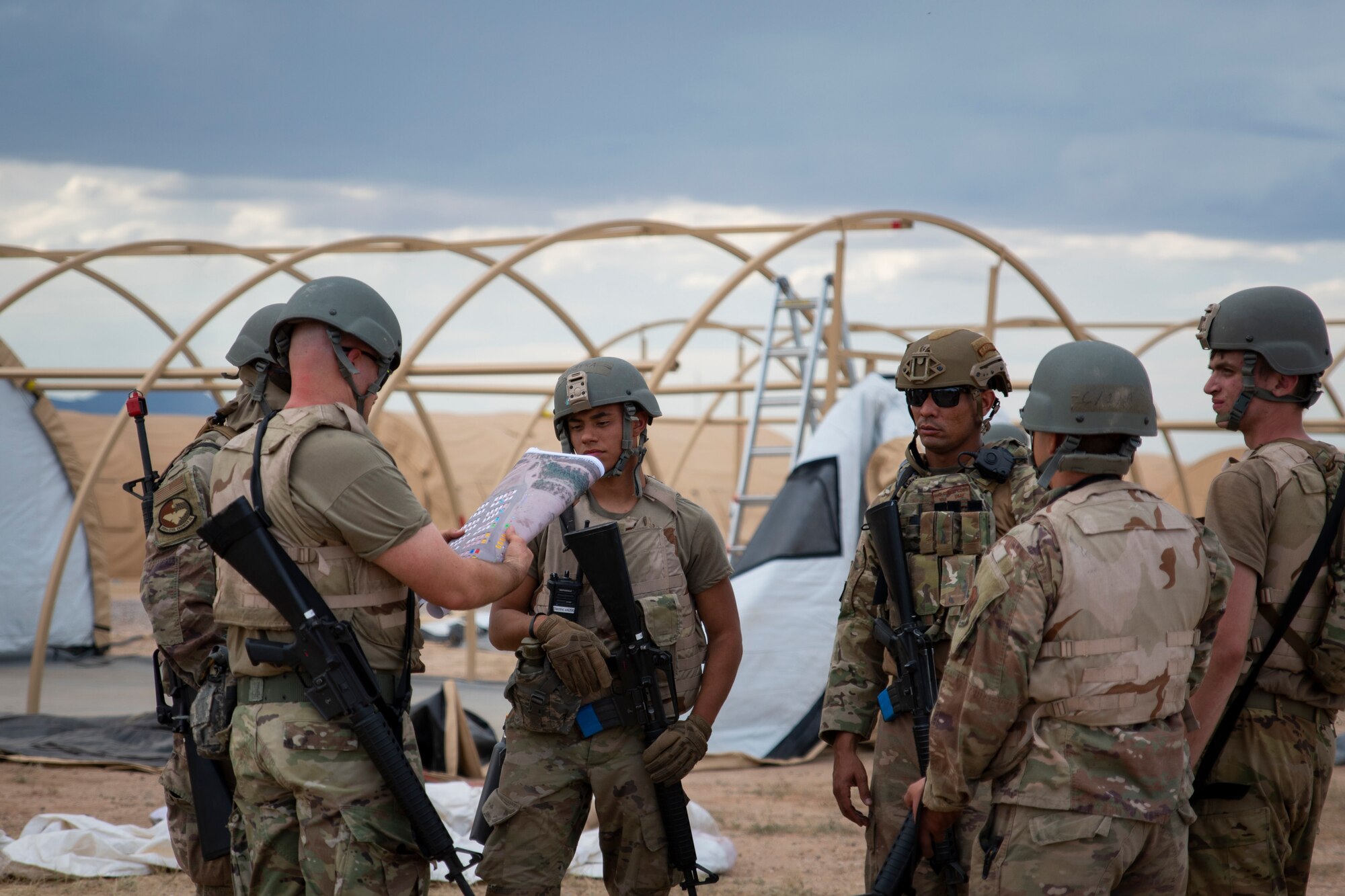 People wearing protective vests and helmets stand around during a meeting.