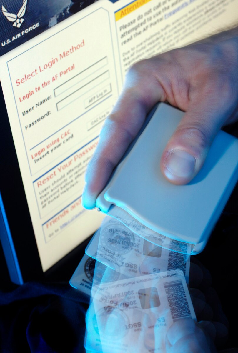 A hand holds a card reader and a common access card.