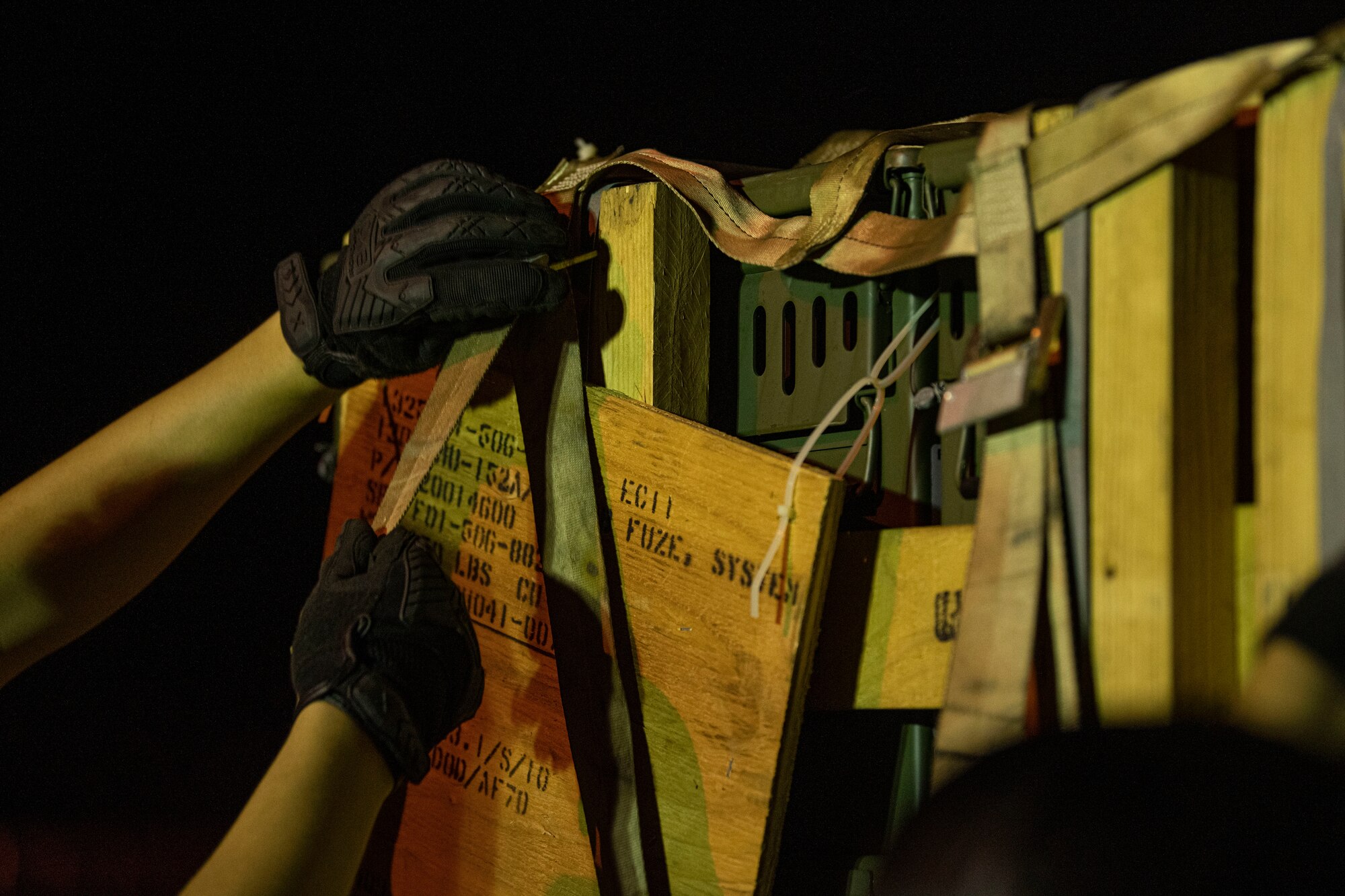 18th MUNS Airman secures straps on a pallet.