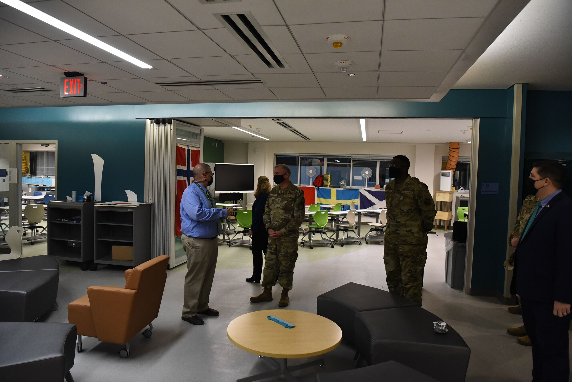 Group of military members in uniform stand in a school and talk to staff members