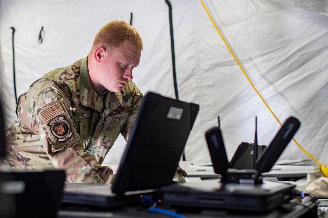 A soldier works on a laptop.