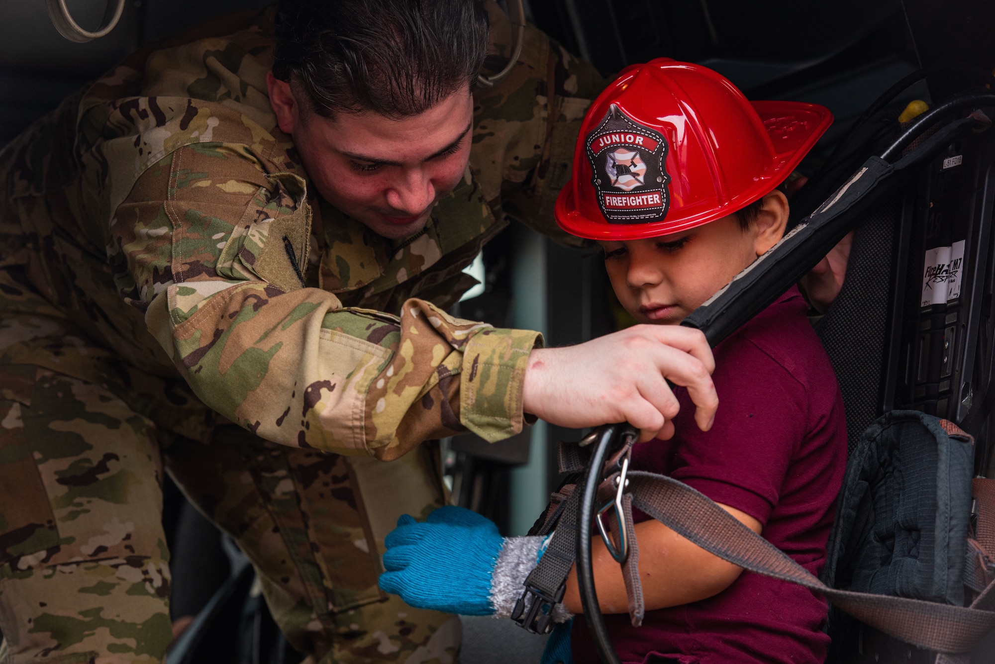 Senior Airman Robles Marrero, 51st Civil Engineer Squadron, fire emergency services driver operator, straps a child into a firetruck passenger seat during a Fire Prevention Week open house event at Osan Air Base, Republic of Korea, Oct. 9, 2021.