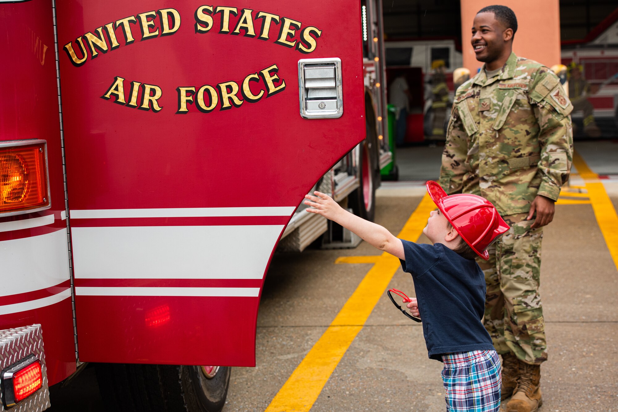 Senior Airman Tasheem Saunders, 51st Civil Engineer Squadron, fire emergency services driver operator, assists children getting in and out of a firetruck during a Fire Prevention Week open house event at Osan Air Base, Republic of Korea, Oct. 9, 2021.