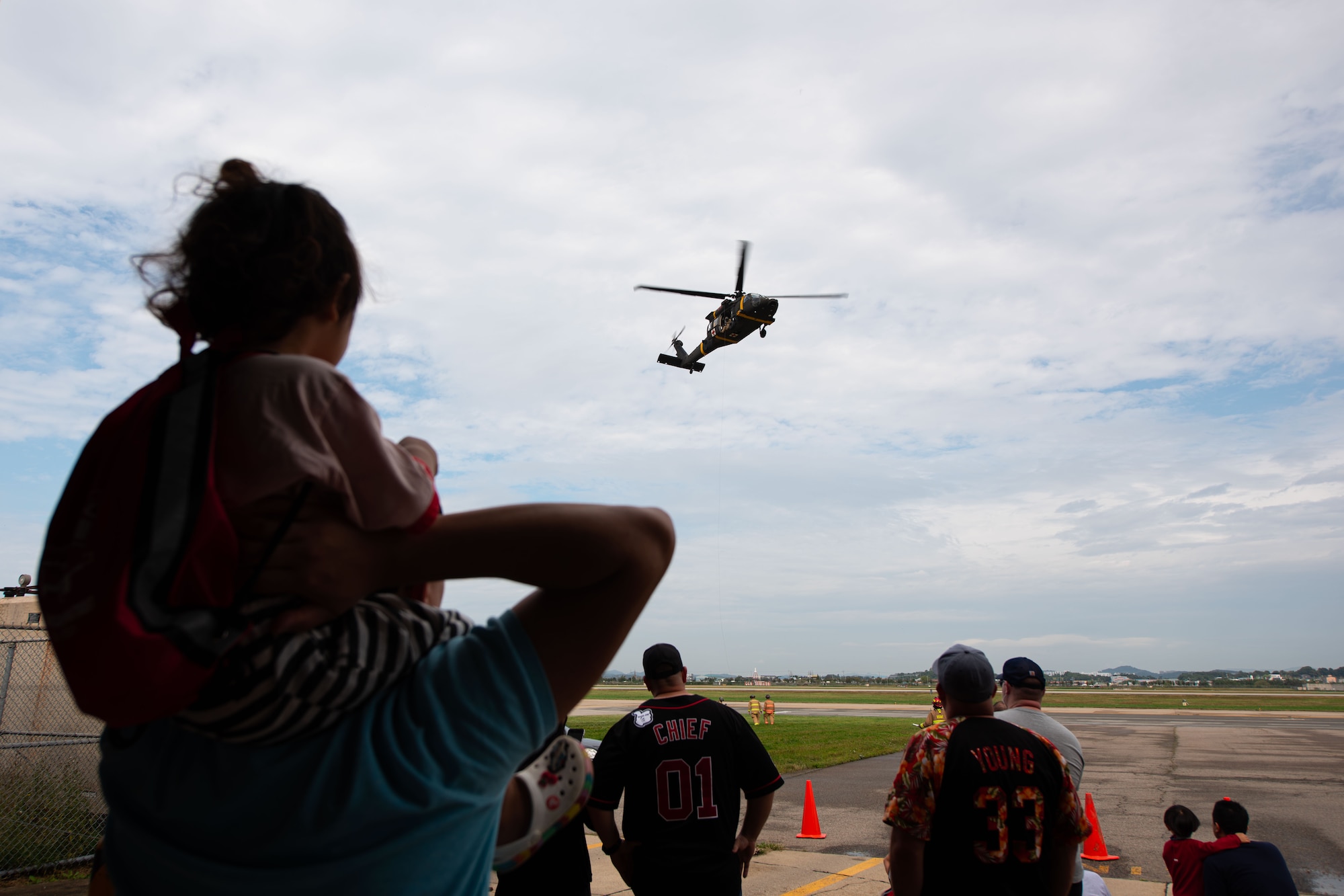 Military service members and their dependents watch a UH-60Q Black Hawk helicopter rescue demonstration during a Fire Prevention Week open house at Osan Air Base, Republic of Korea, Oct. 9, 2021.