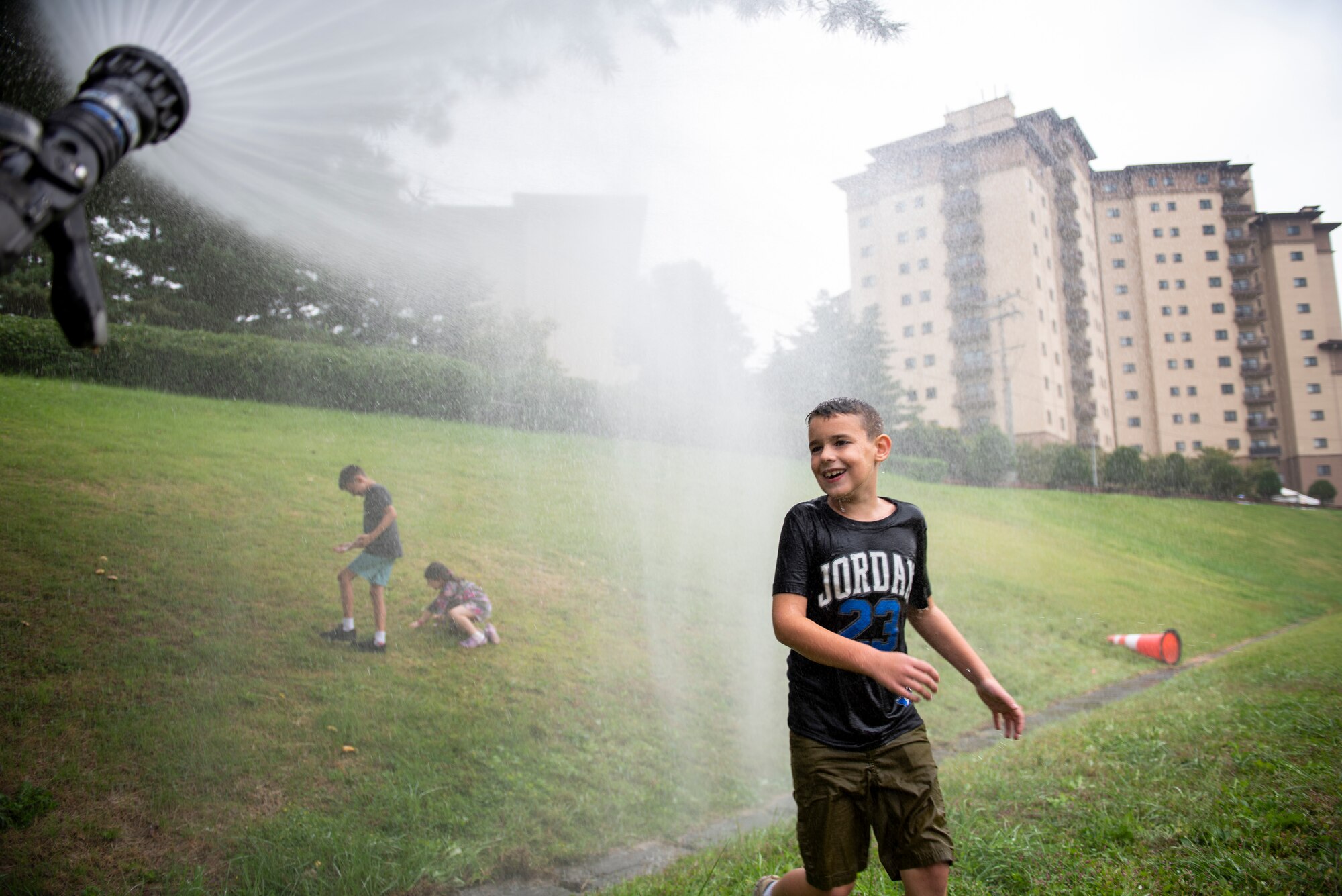 A child attendee plays in sprayed water from a fire hose during the Fire Prevention Week’s Kids Showcase