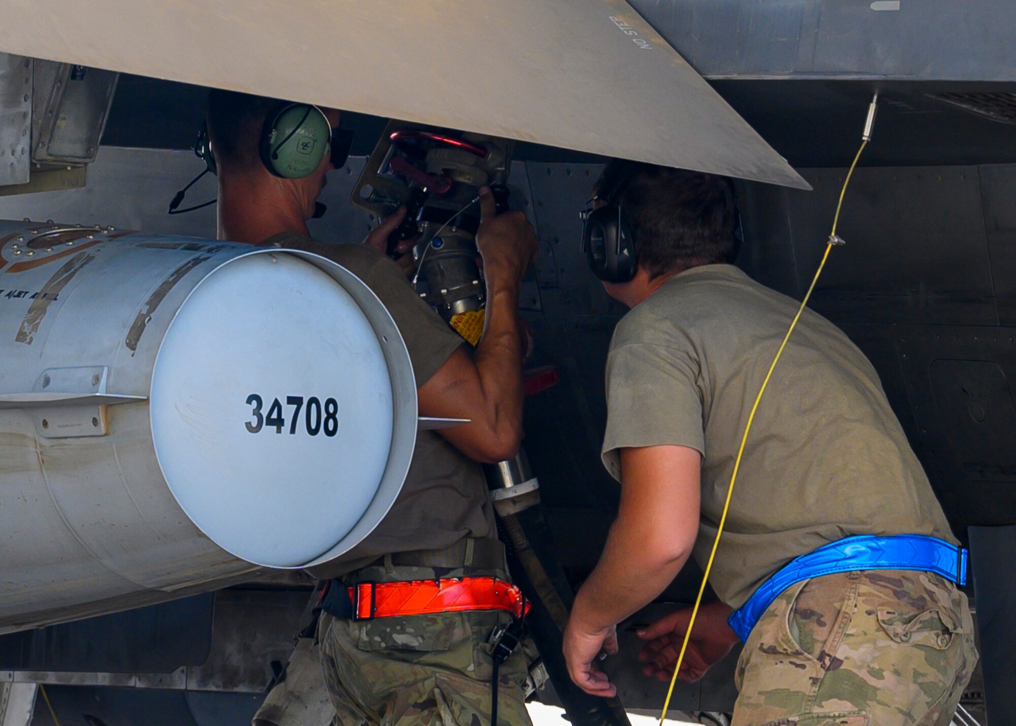 U.S. Air Force Senior Airman Nicholas Kunets, 332nd Air Expeditionary Wing F-15E crew chief, performs a hot pit refueling on a  U.S. F-16 Fighting Falcon while Senior Airman Spencer Daar 378th Expeditionary Logistics Readiness Squadron fuels and distribution airmen supervises Prince Sultan Air Base, Kingdom of Saudi Arabia, May 3, 2021. Maintenance crews assigned to the 332nd and 378th AEWs conducted a hot pit refueling training exchange over the course of several weeks, increasing their agile combat employment capabilities by ensuring both F-16 Fighting Falcons and F-15E Strike Eagles can be refueled by each wing. (U.S. Air Force photo by Senior Airman Samuel Earick)
