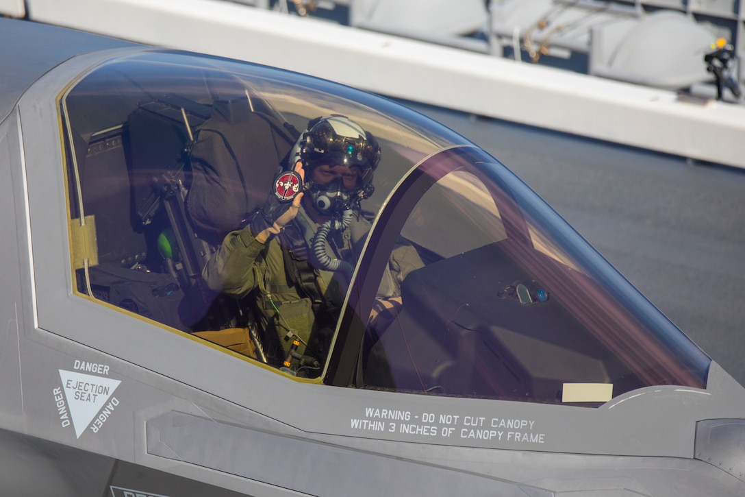 米海兵隊攻撃飛行隊のパイロットがコックピットから「いずも」のワッペンを掲げる、2021年10月３日、海上自衛隊護衛艦「いずも」艦上