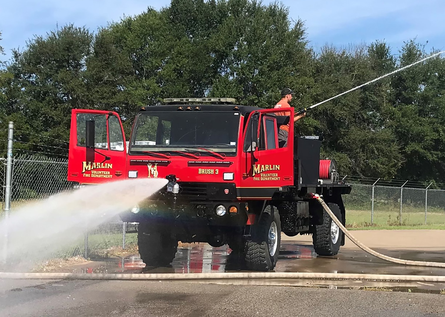 A former military truck displays its new ability to spray water during a demonstration in a parking lot where it sprayed water.