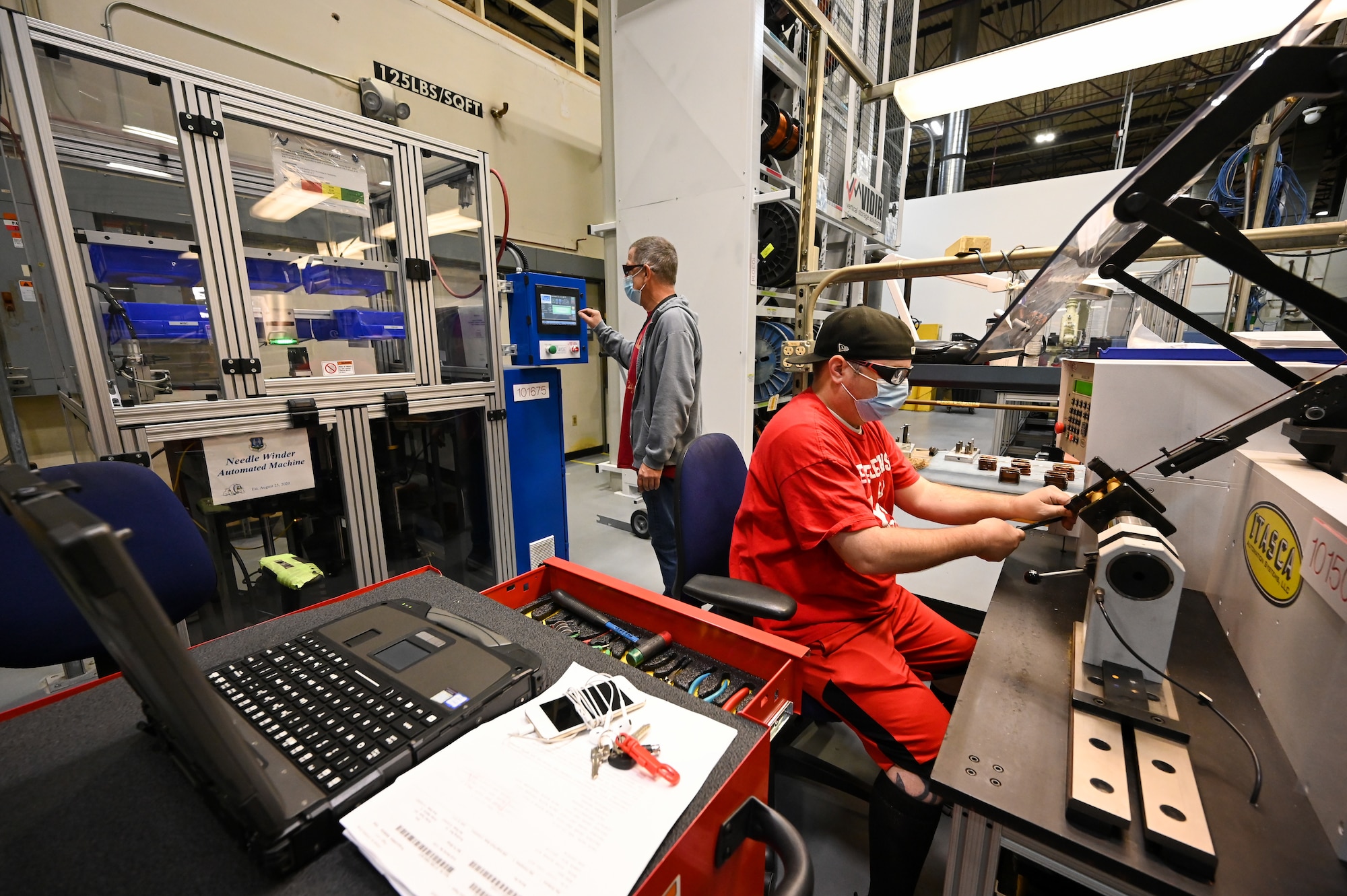 Matthew Noorda, right, and Michael Sherman, 526th Electronics Maintenance Squadron, operate automated winding equipment at Hill Air Force Base, Utah, Sept. 24, 2021. The 526th EMXS replaced its process of winding and forming coils by hand with automated equipment in order to save time and money while improving product quality and shop safety. (U.S. Air Force photo by R. Nial Bradshaw)