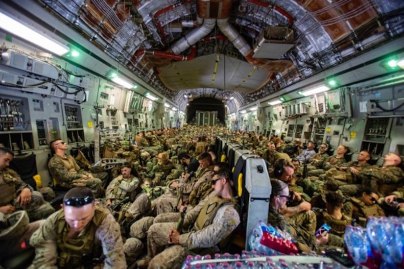 Marines sleep in a crowded plane.
