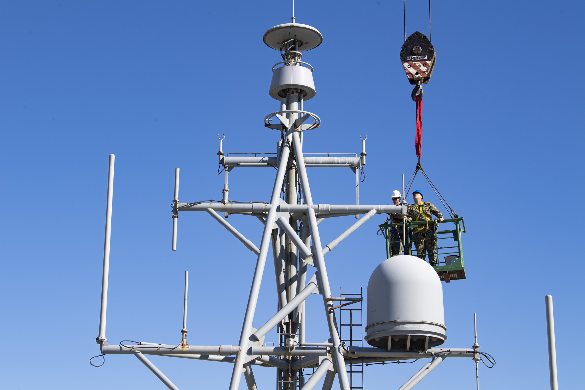 Information System Technician 2nd Class Nathan A. Milca, right, and Electronics Technician 2nd Class Drake W. Childers perform annual maintenance on the forward house antennae aboard the Expeditionary Sea Base USS Hershel "Woody" Williams (ESB 4) while moored in Cape Town, South Africa for a regularly scheduled maintenance period, Oct. 5, 2021.