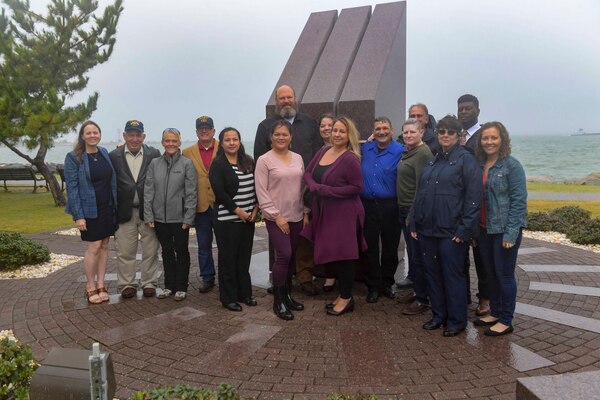 NAVAL STATION NORFOLK (Oct. 12, 2021) USS Cole survivors pose for a group photo at the USS Cole Memorial. Cole friends, family and shipmates gathered on board Naval Station Norfolk for the 21st remembrance of the USS Cole terrorist attack. Seventeen Sailors lost their lives and another 39 sustained injuries while the crew worked for 96 consecutive hours to keep the ship afloat. (U.S. Navy photo by Mass Communication Specialist 1st Class Jacob Milham)