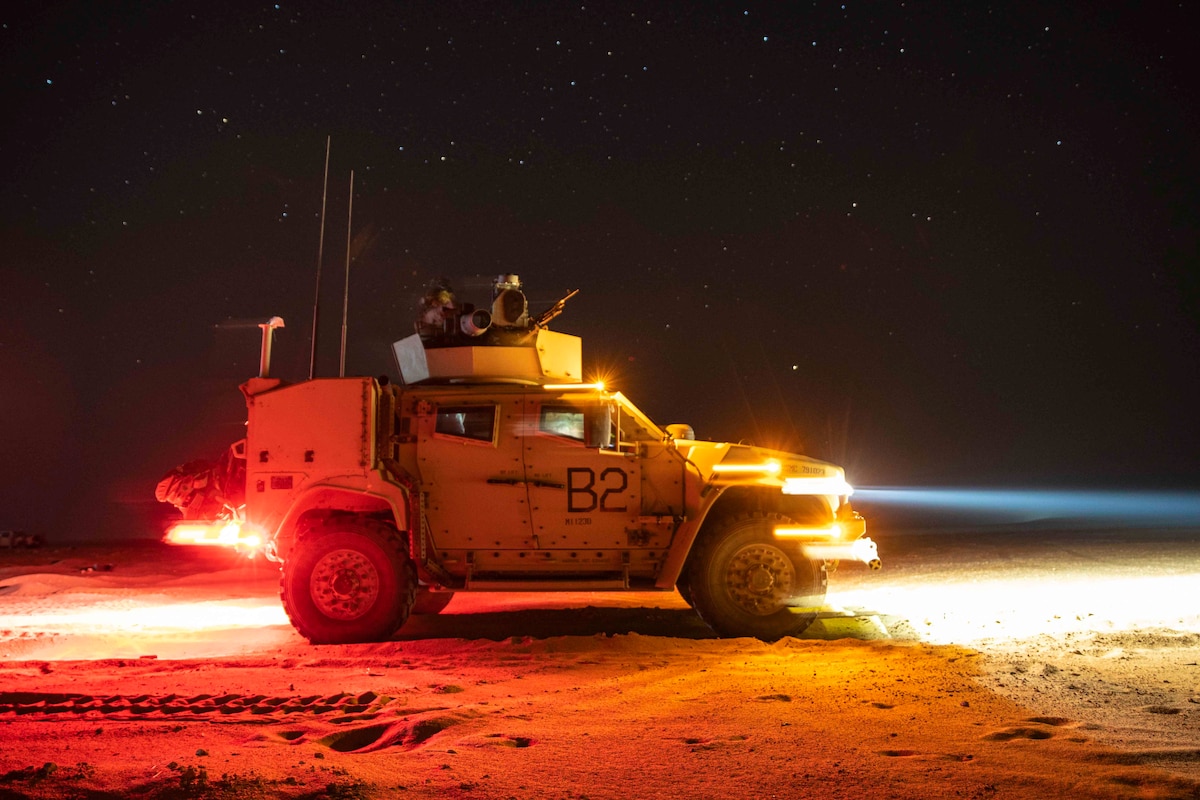 Marines ride in a military vehicle at night.