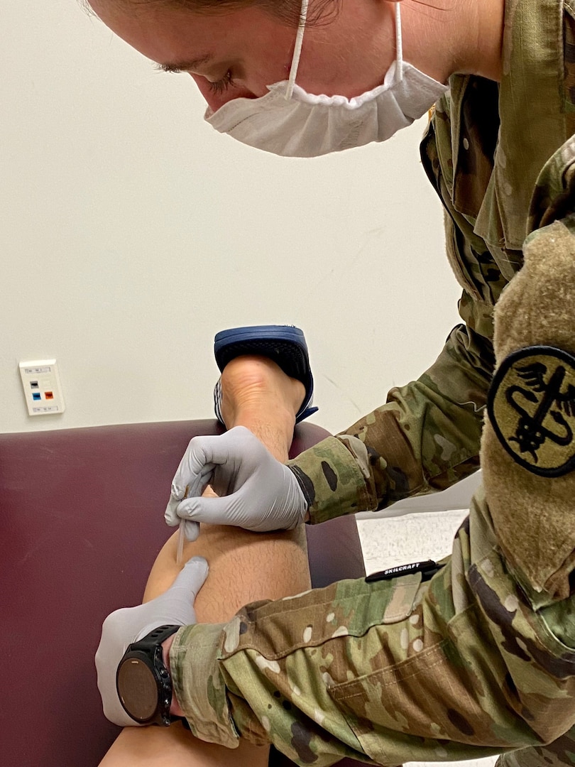 Capt. Jessica Carrignan, assistant chief of physical therapy, demonstrates dry needling therapy.