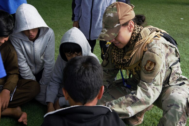 An Airman assigned to Task Force-Holloman interacts with Afghan children at Holloman Air Force Base, New Mexico, Oct. 1, 2021. The Department of Defense, through U.S. Northern Command, and in support of the Department of State and Department of Homeland Security, is providing transportation, temporary housing, medical screening, and general support for at least 50,000 Afghan evacuees at suitable facilities, in permanent or temporary structures, as quickly as possible. This initiative provides Afghan evacuees essential support at secure locations outside Afghanistan. (U.S. Navy photo by Mass Communications Specialist 1st Class Sarah Rolin)