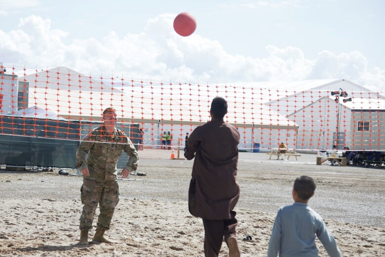 An Afghan boy serves the ball to an awaiting Soldier attached to Task Force-Holloman during an impromptu volleyball game at Holloman Air Force Base, New Mexico, Oct. 1, 2021. The Department of Defense, through U.S. Northern Command, and in support of the Department of State and Department of Homeland Security, is providing transportation, temporary housing, medical screening, and general support for at least 50,000 Afghan evacuees at suitable facilities, in permanent or temporary structures, as quickly as possible. This initiative provides Afghan evacuees essential support at secure locations outside Afghanistan. (U.S. Navy photo by Mass Communications Specialist 1st Class Sarah Rolin)