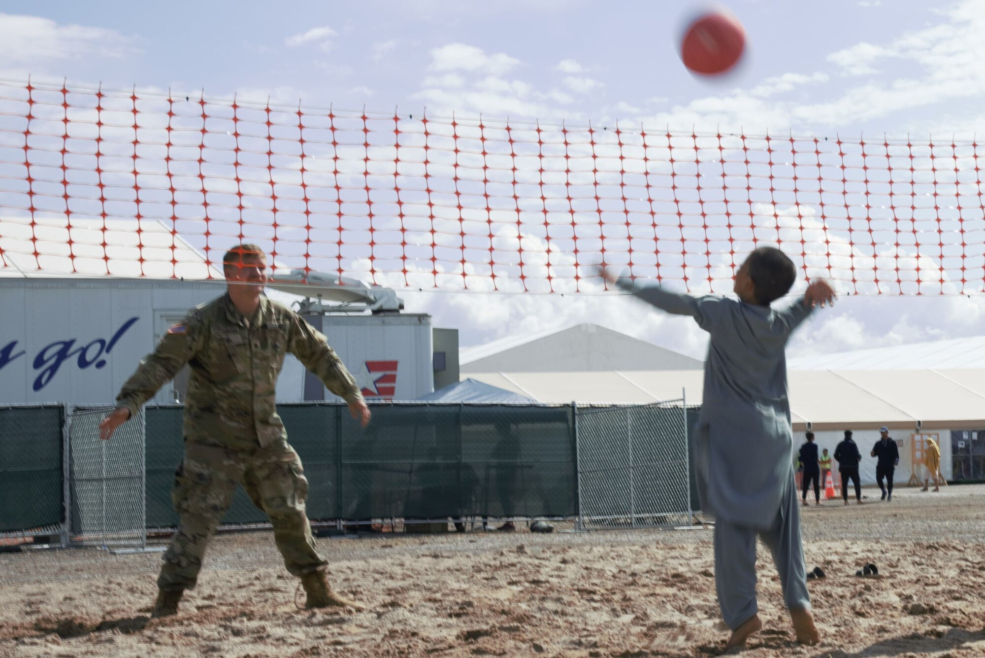 An intense volleyball game ensues between a Soldier assigned to Task Force-Holloman and an Afghan boy on Aman Omid Village on Holloman Air Force Base, New Mexico, Oct. 1, 2021. The Department of Defense, through U.S. Northern Command, and in support of the Department of State and Department of Homeland Security, is providing transportation, temporary housing, medical screening, and general support for at least 50,000 Afghan evacuees at suitable facilities, in permanent or temporary structures, as quickly as possible. This initiative provides Afghan evacuees essential support at secure locations outside Afghanistan. (U.S. Navy photo by Mass Communications Specialist 1st Class Sarah Rolin)